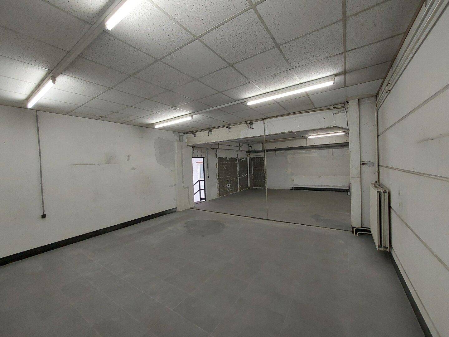 Geräumiger Gewerberaum mit unterschiedlichen Bodenbelägen und Deckenbeleuchtung, vielseitig nutzbar.