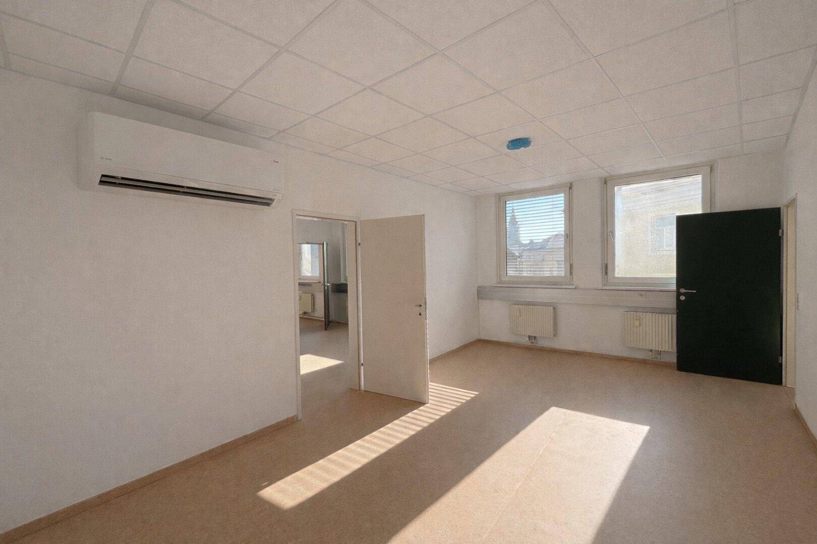 Geräumiges Büro mit Klimaanlage, hellem Boden und Fenstern, die viel Tageslicht hereinlassen.