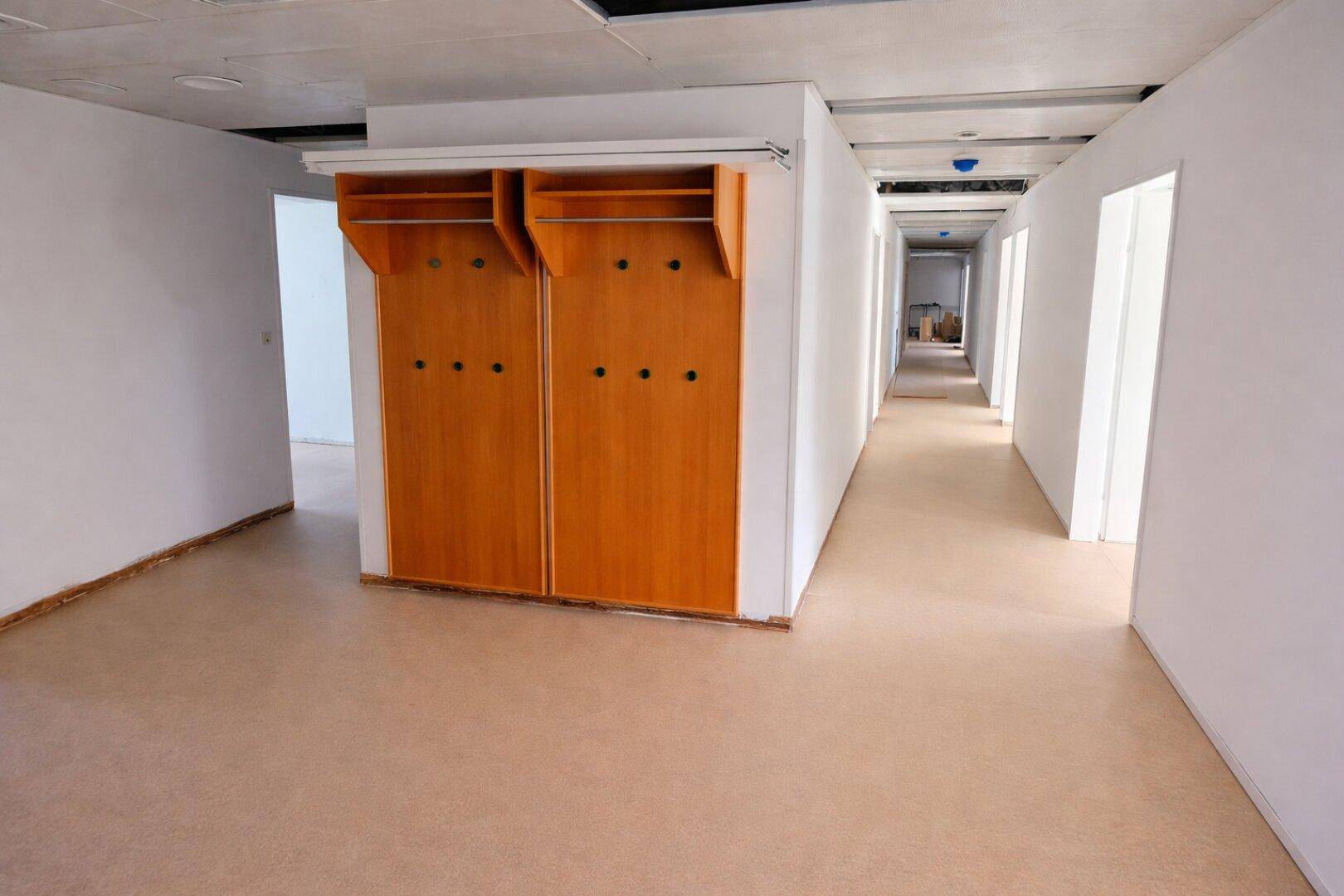 Langer Flur mit integrierten Holzgarderoben und Türen, die zu weiteren Räumen führen.