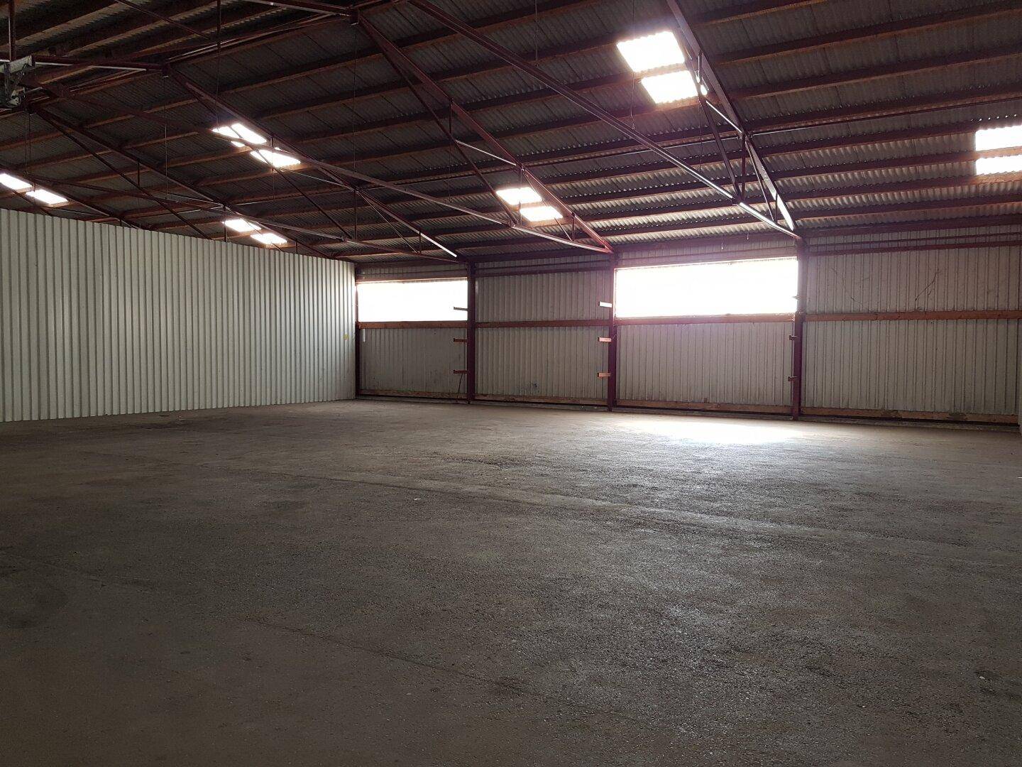 Leere Industriehalle mit hoher Decke, Wellblechdach und natürlichem Lichteinfall durch Oberlichter.
