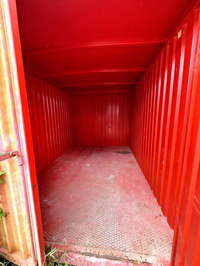 Innenansicht eines roten Schiffscontainers mit Wellblechwänden und einem robusten Riffelblechboden.