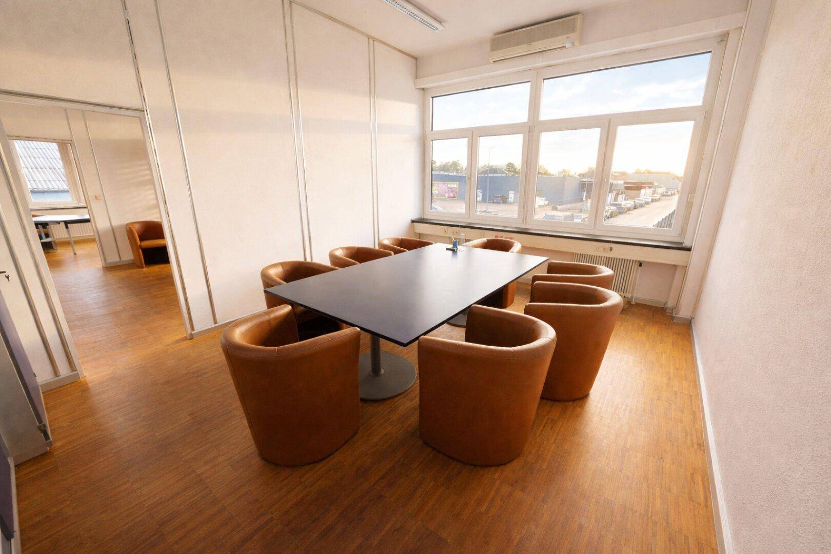 Konferenzraum mit großem schwarzen Tisch, braunen Stühlen und weitem Blick aus den Fenstern.