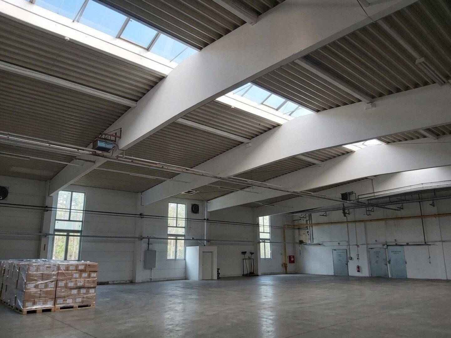 Helle Lagerhalle mit hohen Fenstern und Oberlichtern, die für reichlich natürliches Licht sorgen.