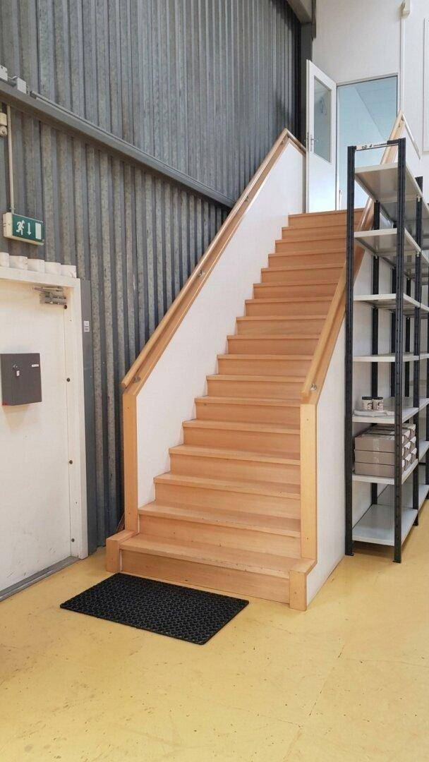 Helle Holztreppe in einem gewerblichen Bereich mit gelbem Vinylboden und Metallwänden.