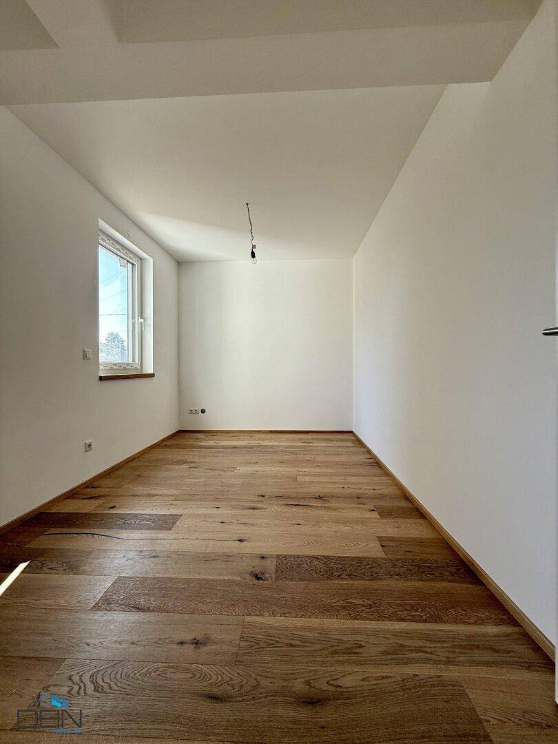 Helles Schlafzimmer mit Holzboden und einem Fenster, bereit zur Einrichtung.