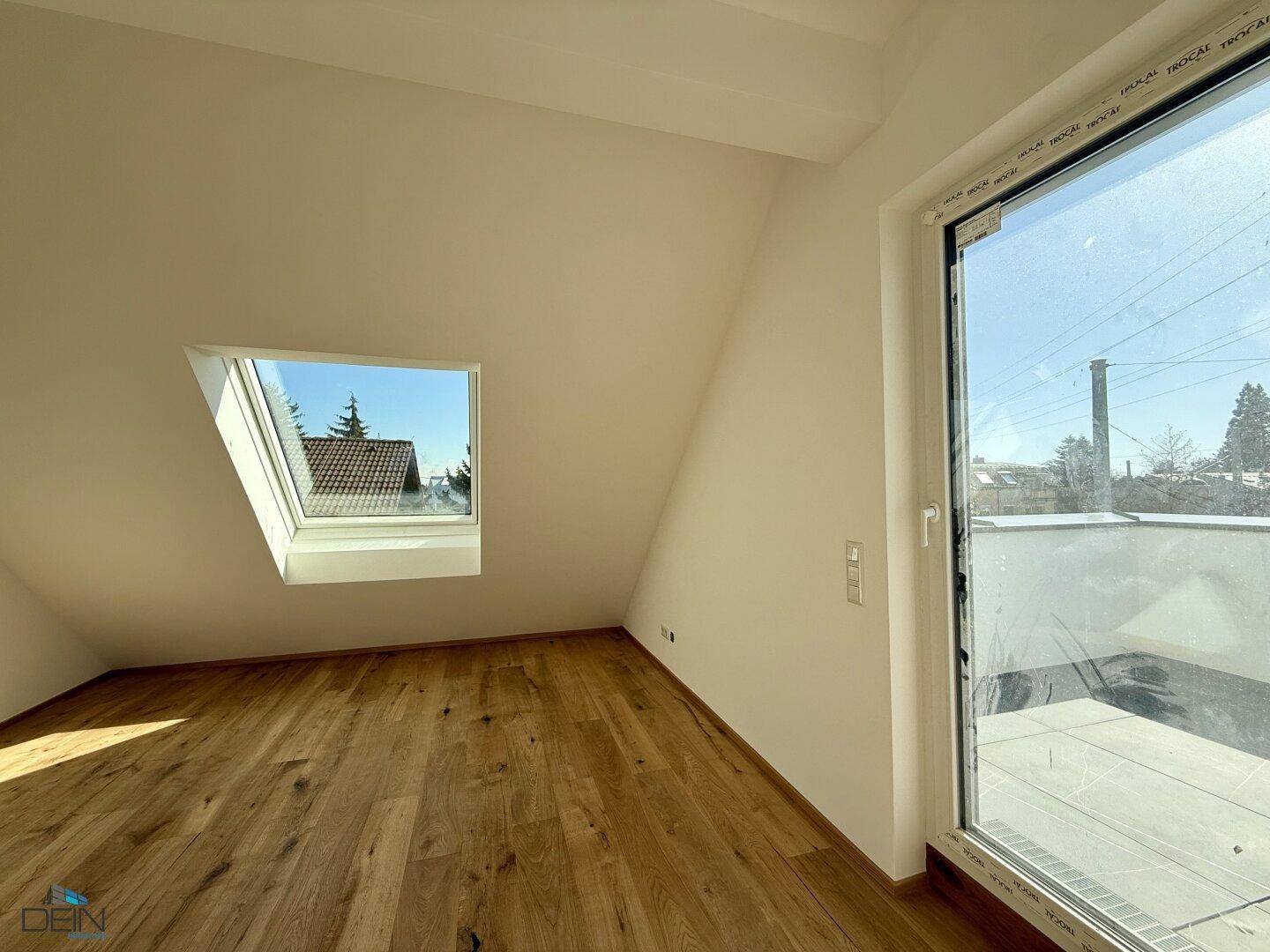 Dachzimmer mit Dachfenster und Zugang zu einer Dachterrasse.