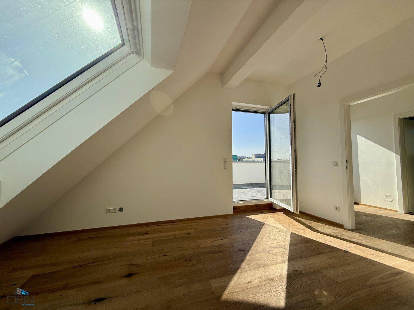 Lichtdurchflutetes Dachzimmer mit großem Dachfenster und Terrassenzugang.