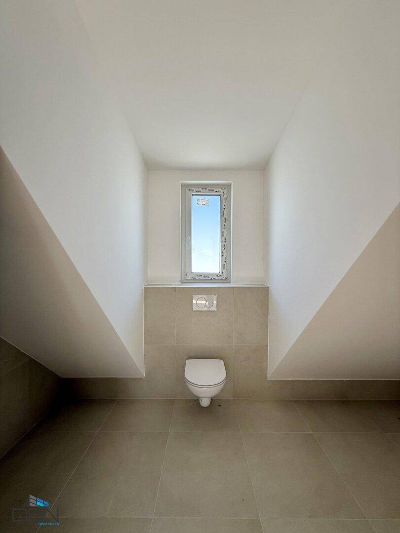 Gäste-WC im Dachgeschoss mit wandhängender Toilette und Fenster.