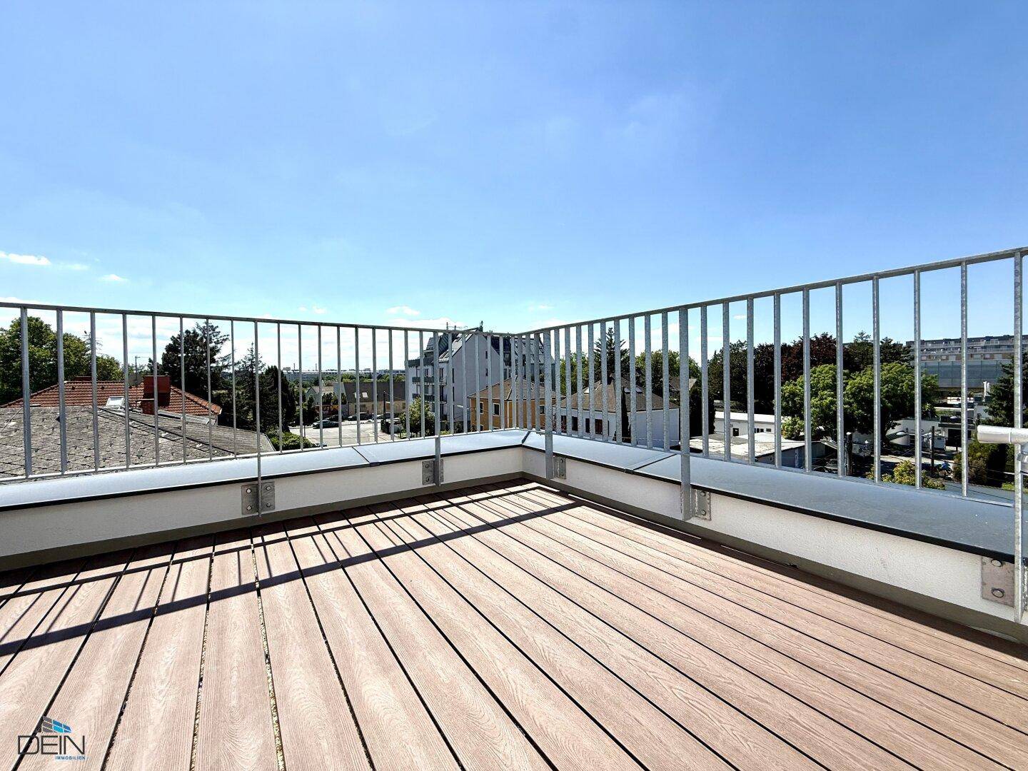 Geräumige Dachterrasse mit Holzboden und weitem Blick über die umliegende Wohngegend.