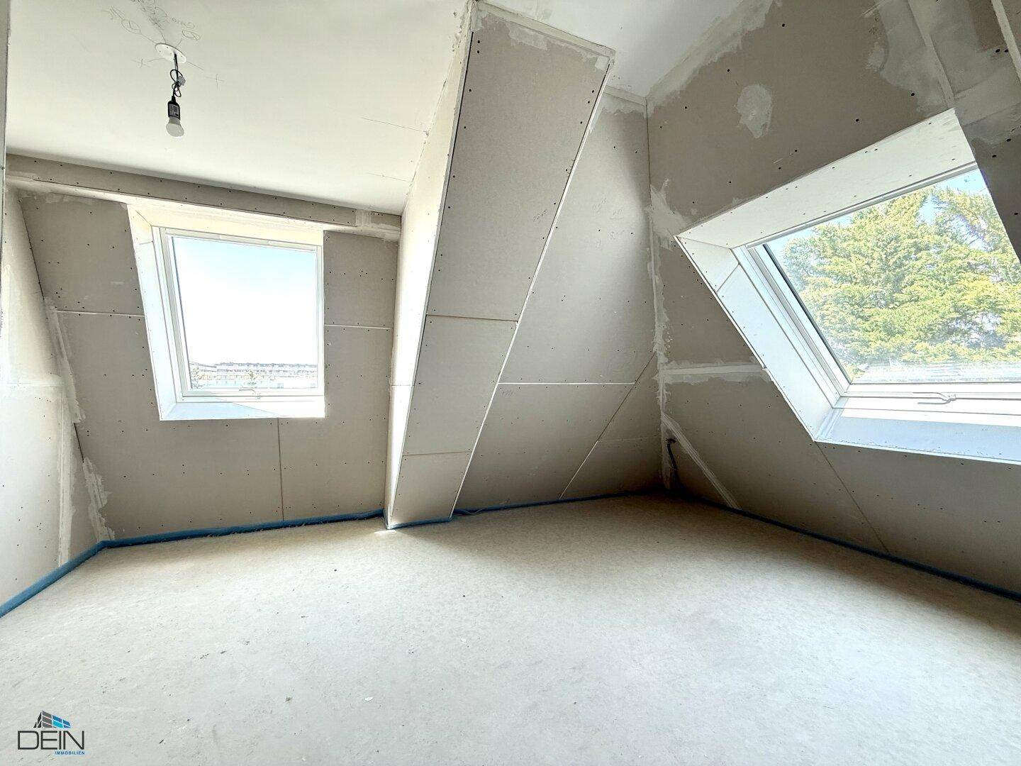 Rohbauzimmer mit Dachschrägen und zwei Dachfenstern, die den Raum mit Tageslicht versorgen.