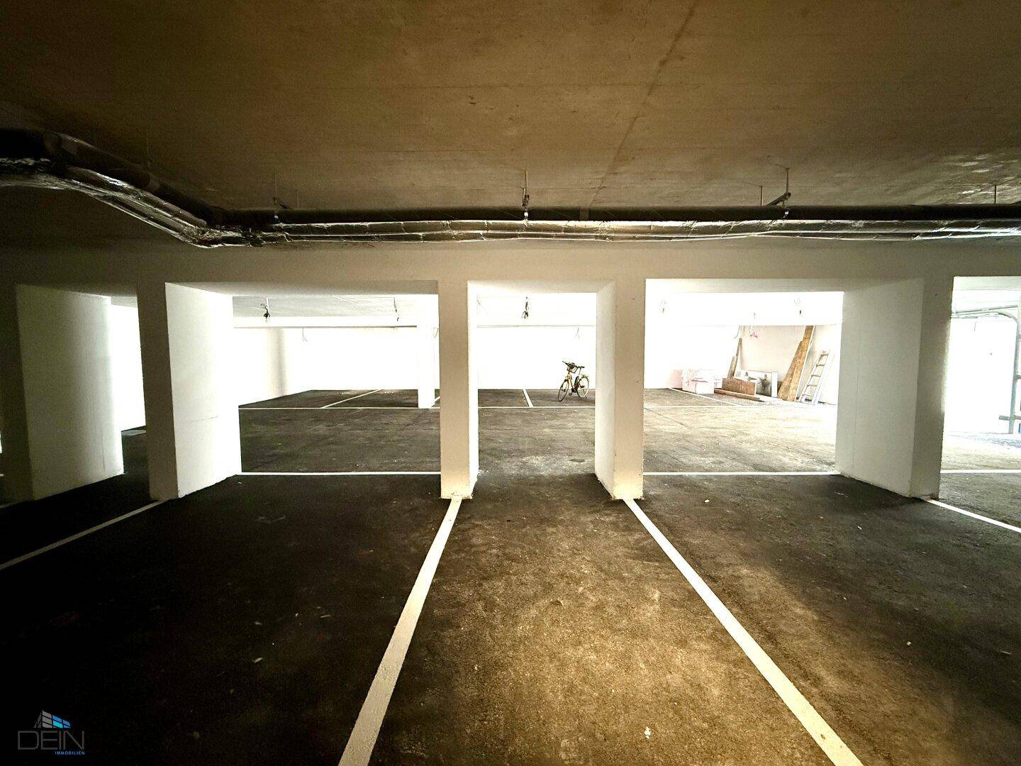 Geräumige Tiefgarage mit markierten Stellplätzen und Betonpfeilern, noch im Bauzustand.