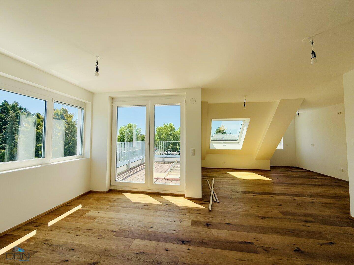Heller Wohnbereich im Dachgeschoss mit Holzboden, großen Fenstern und Zugang zur Terrasse.