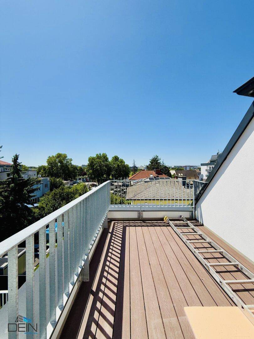 Geräumige Dachterrasse mit Holzdielen und weitem Blick über die Umgebung.