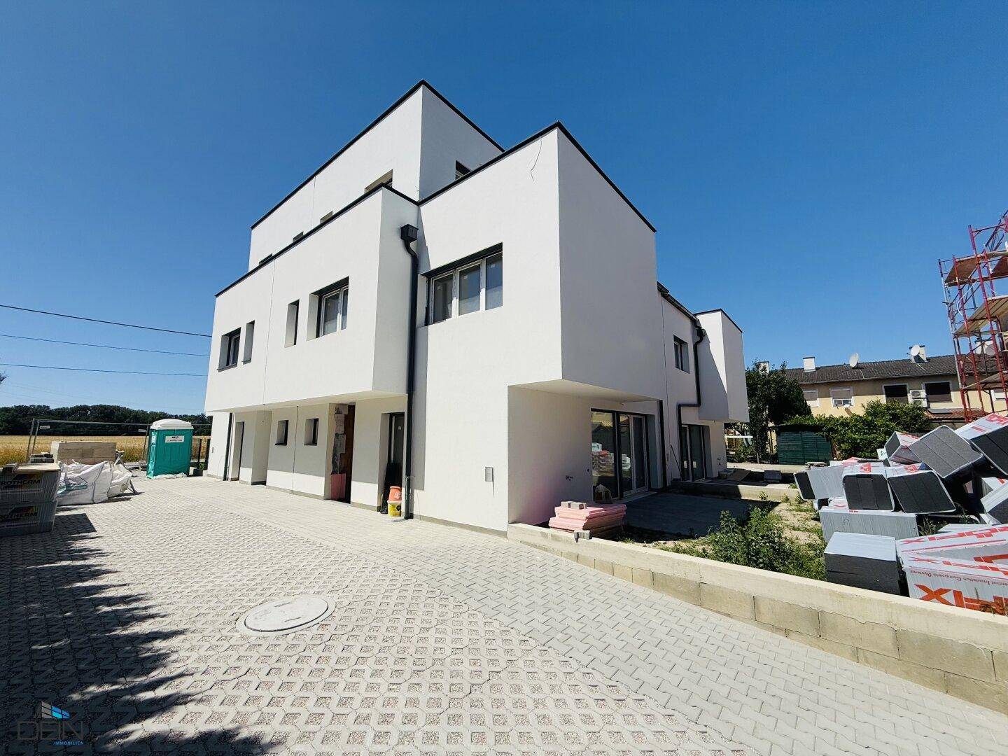 Moderne Neubauten mit weißer Fassade und Baustellenbereich im Vordergrund.