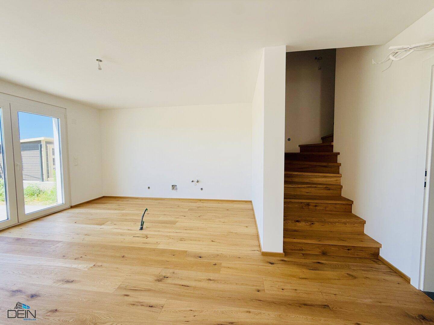 Heller Wohnbereich mit Eichenparkett und offener Holztreppe, bereit für die individuelle Gestaltung.