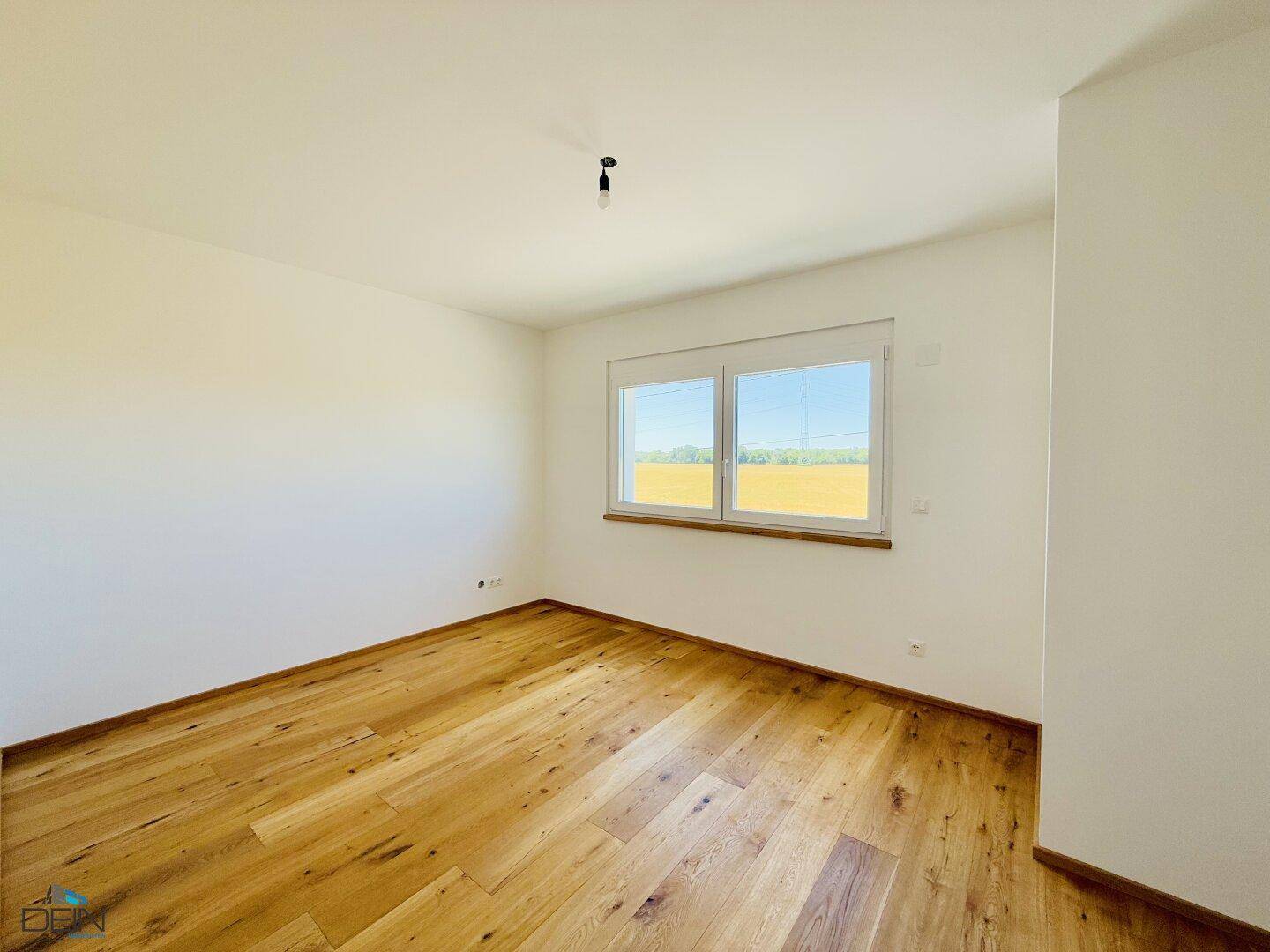 Schlafzimmer mit Eichenparkett und weitem Blick über die umliegende Landschaft.