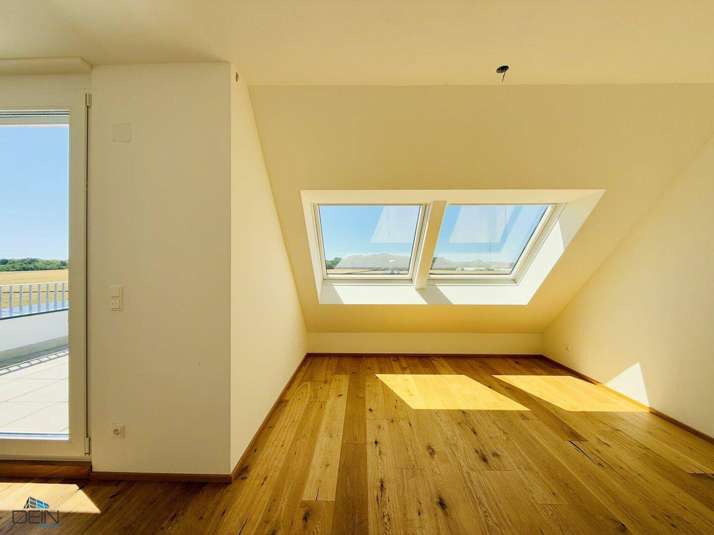 Helles Dachzimmer mit Eichenparkett, Dachfenstern und Zugang zur Dachterrasse.