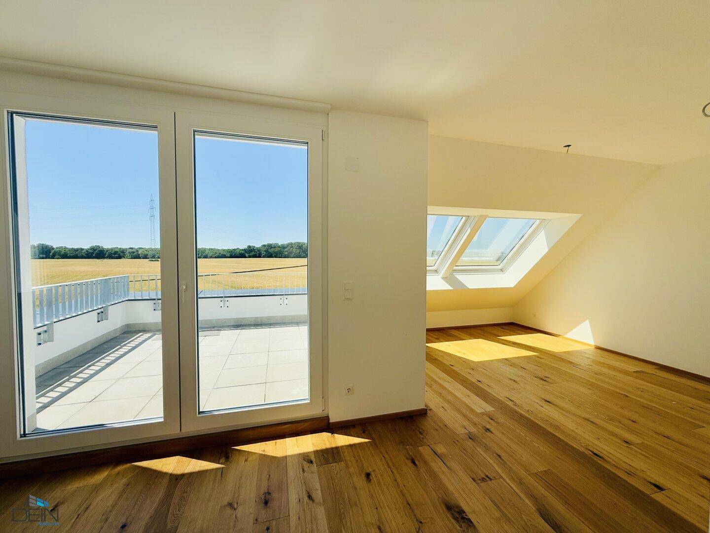 Dachzimmer mit Eichenparkett, Dachfenstern und direktem Zugang zur sonnigen Dachterrasse.