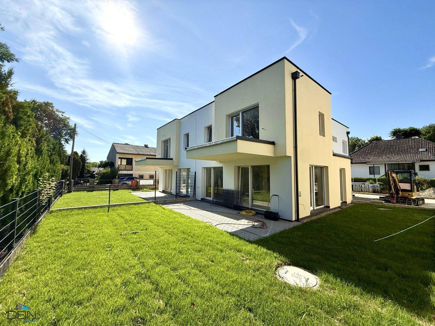 Rückansicht einer modernen Doppelhaushälfte mit weitläufigem Garten und sonniger Terrasse.