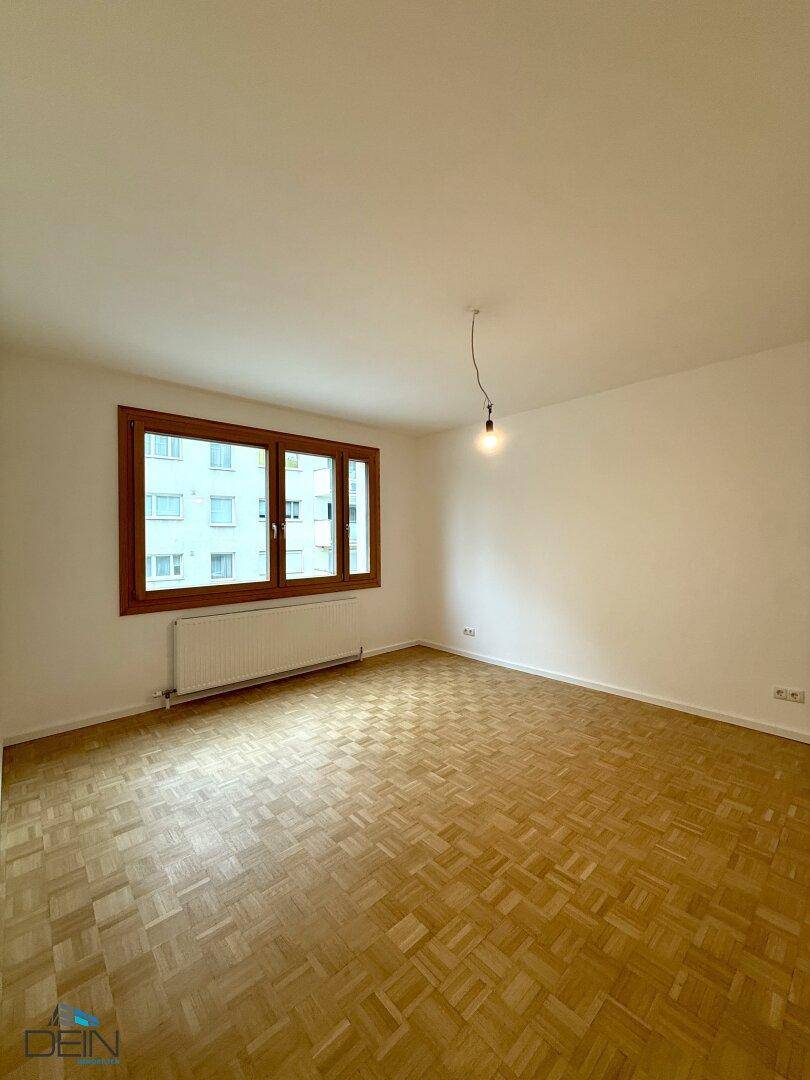 Heller Raum mit Parkettboden und großem Fenster, ideal als Schlaf- oder Wohnzimmer nutzbar.