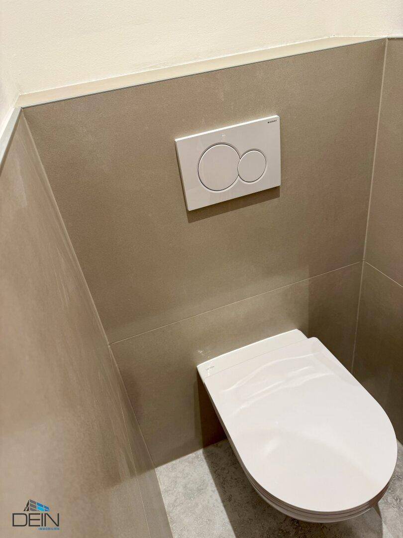 Modernes Gäste-WC mit wandhängender Toilette und beigefarbenen Fliesen an den Wänden.