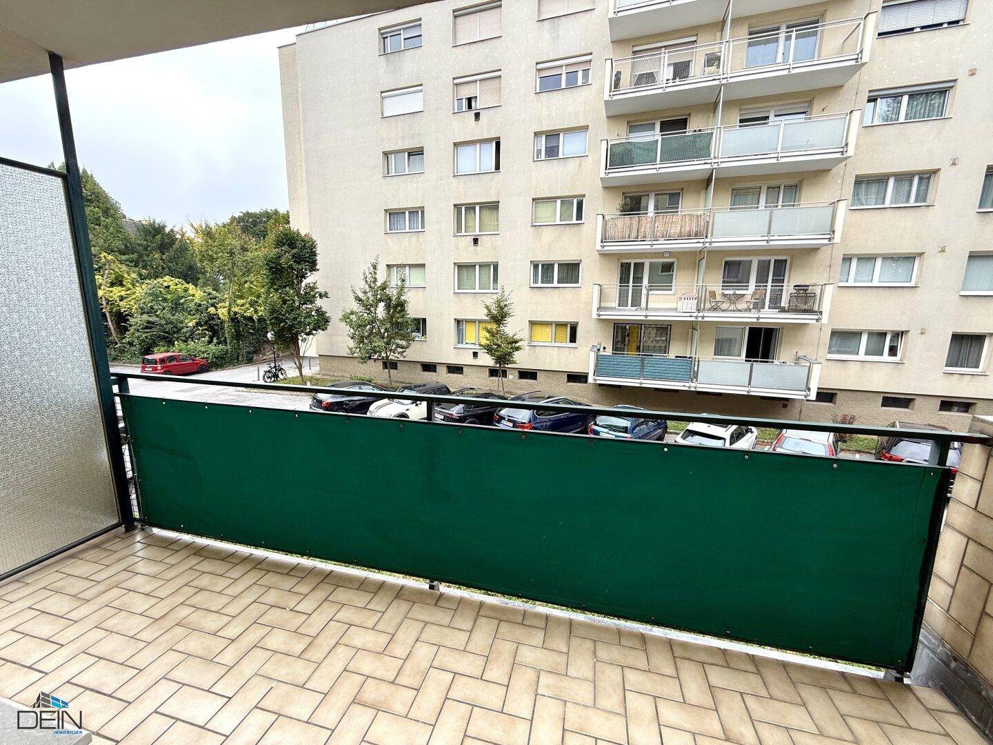 Balkon mit Fliesenboden und Blick auf den Innenhof und die umliegenden Gebäude.