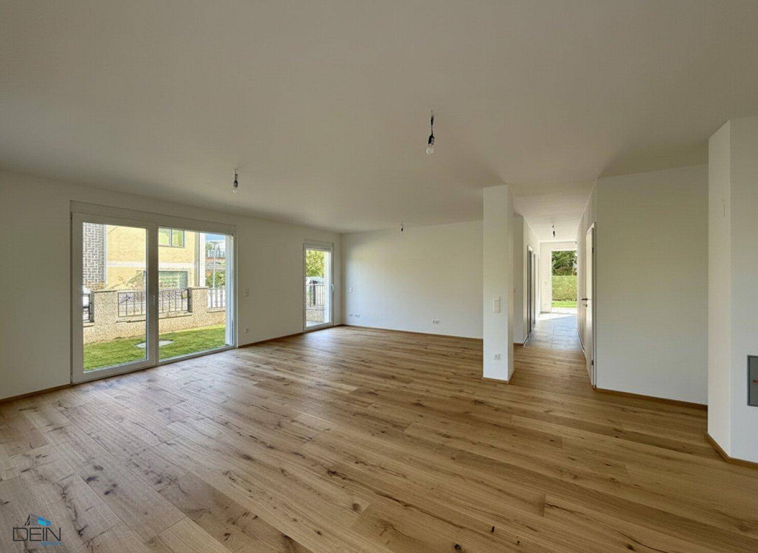 Heller, leerer Wohnbereich mit Holzboden und Zugang zu einem Außenbereich.