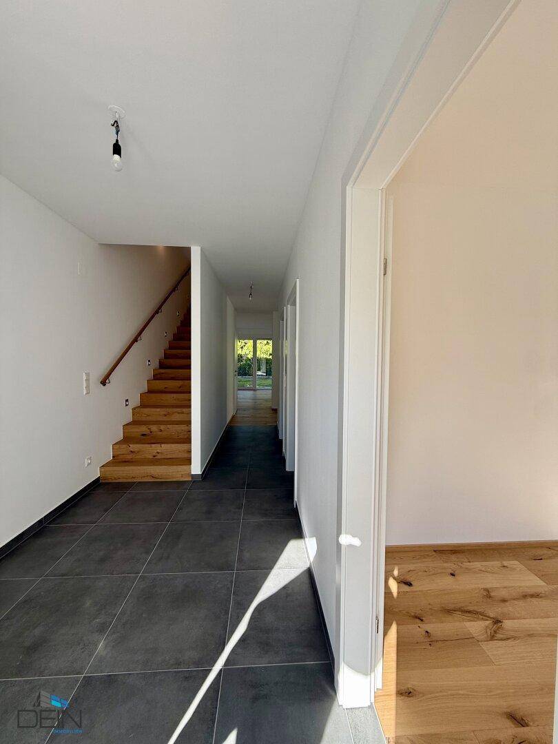 Heller Flur mit Fliesenboden und eleganter Holztreppe, die in die oberen Etagen führt.