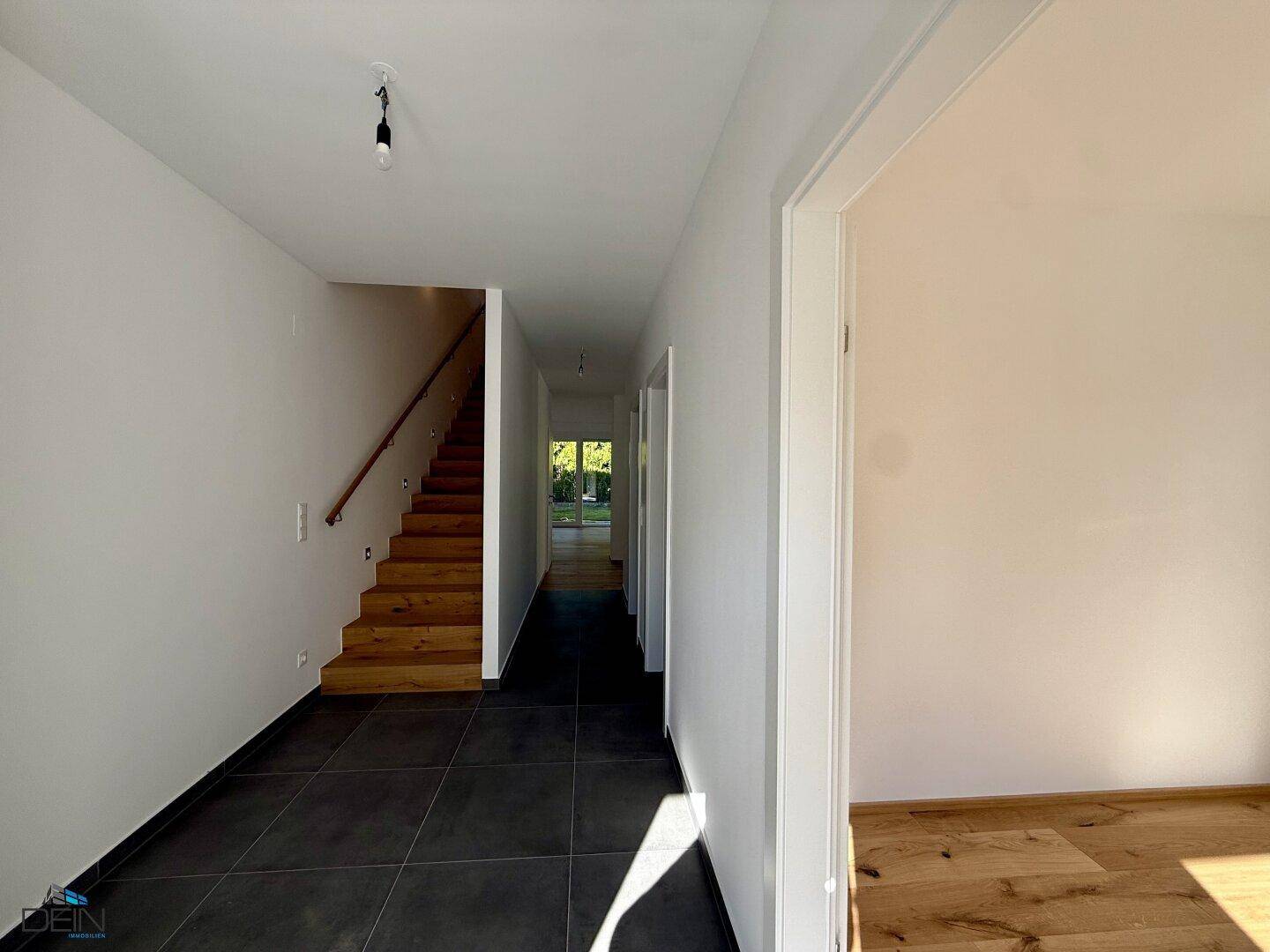 Heller Flur mit Fliesenboden und eleganter Holztreppe, die in die oberen Etagen führt.