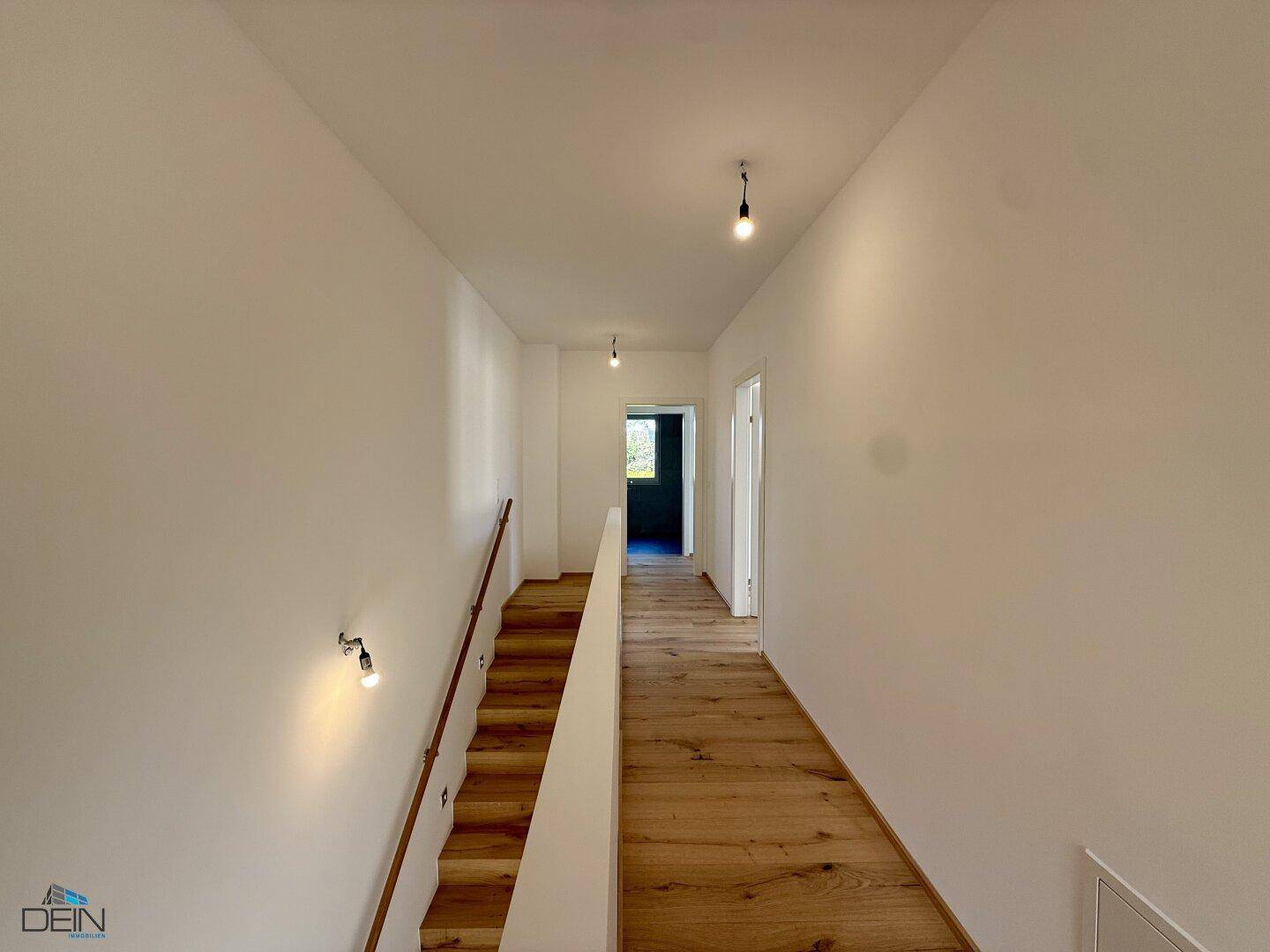 Oberer Flur mit Holzboden und Blick in den unteren Bereich über die offene Treppe.