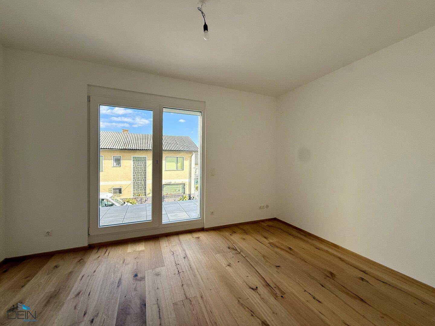 Schlafzimmer mit Holzboden und großem Terrassenzugang, der viel Licht spendet und einen Außenbereich verbindet.