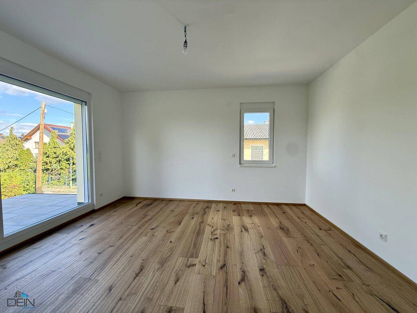 Schlafzimmer mit Holzboden und Fenster, das den Raum mit natürlichem Licht erfüllt und eine ruhige Atmosphäre bietet.