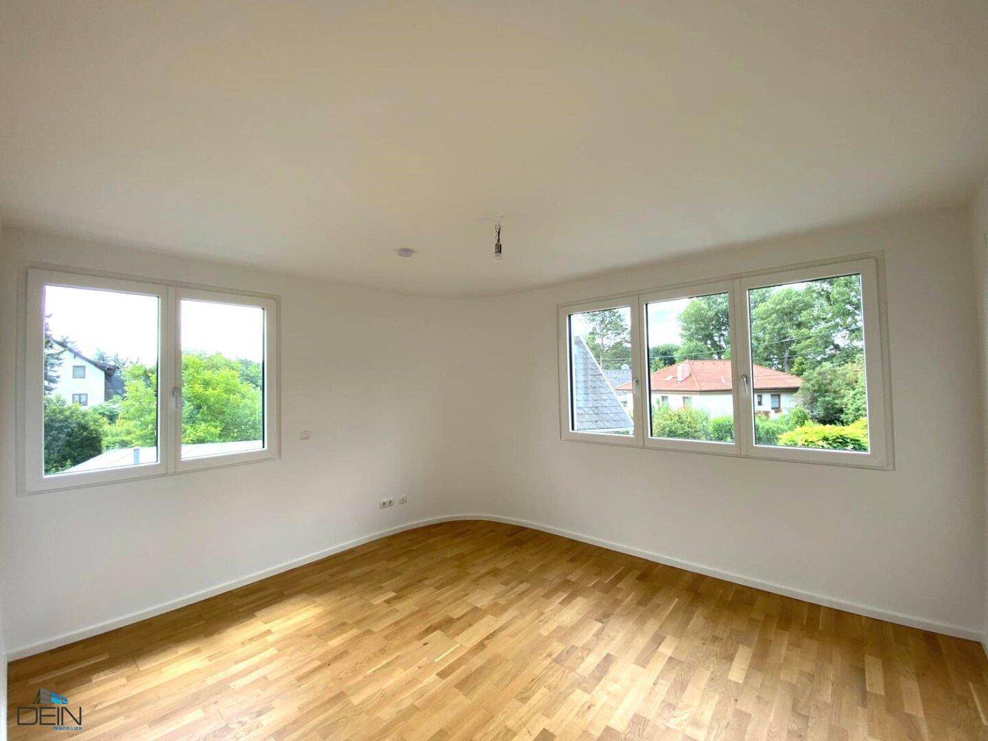 Geräumiges Schlafzimmer mit Holzboden und mehreren Fenstern für eine helle Atmosphäre.