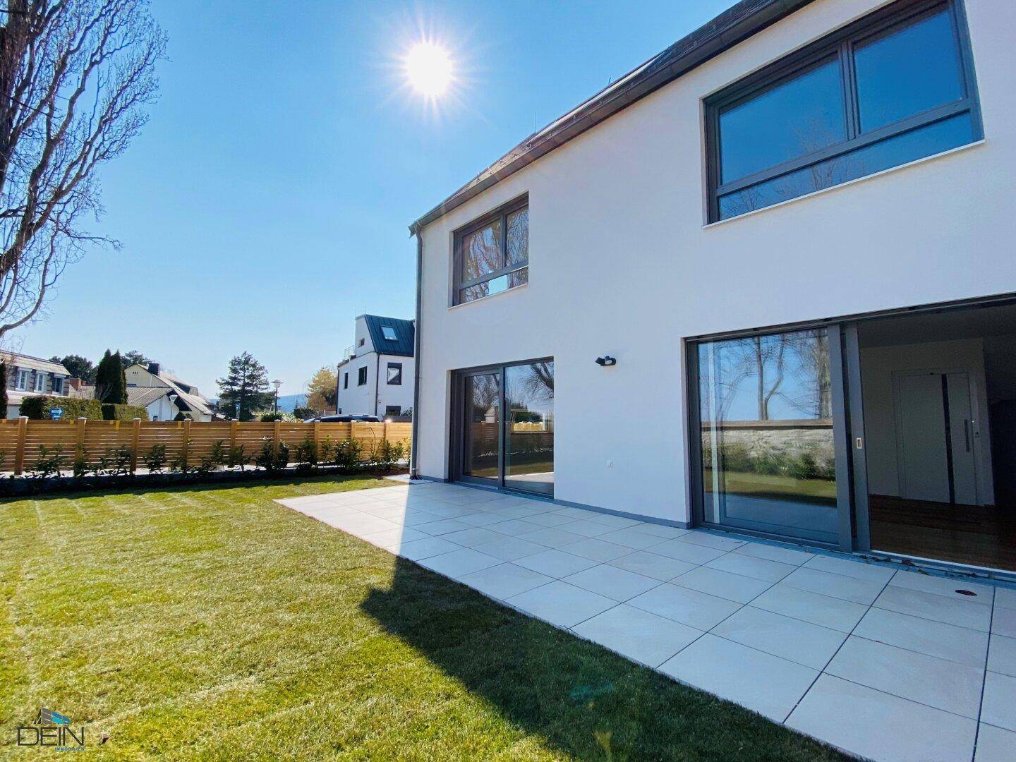 Sonniger Gartenbereich mit großer Terrasse und Zugang zum modernen Reihenhaus.