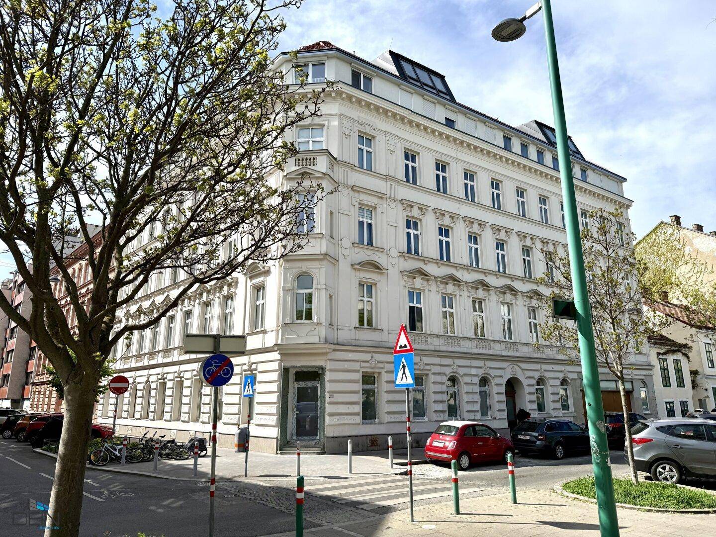 Historisches Eckgebäude in der Stadt mit klassischer Architektur und vielen Fenstern.