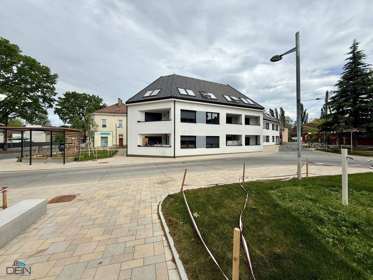 Modernes Mehrfamilienhaus mit weißer Fassade, großen Fenstern und Balkonen.