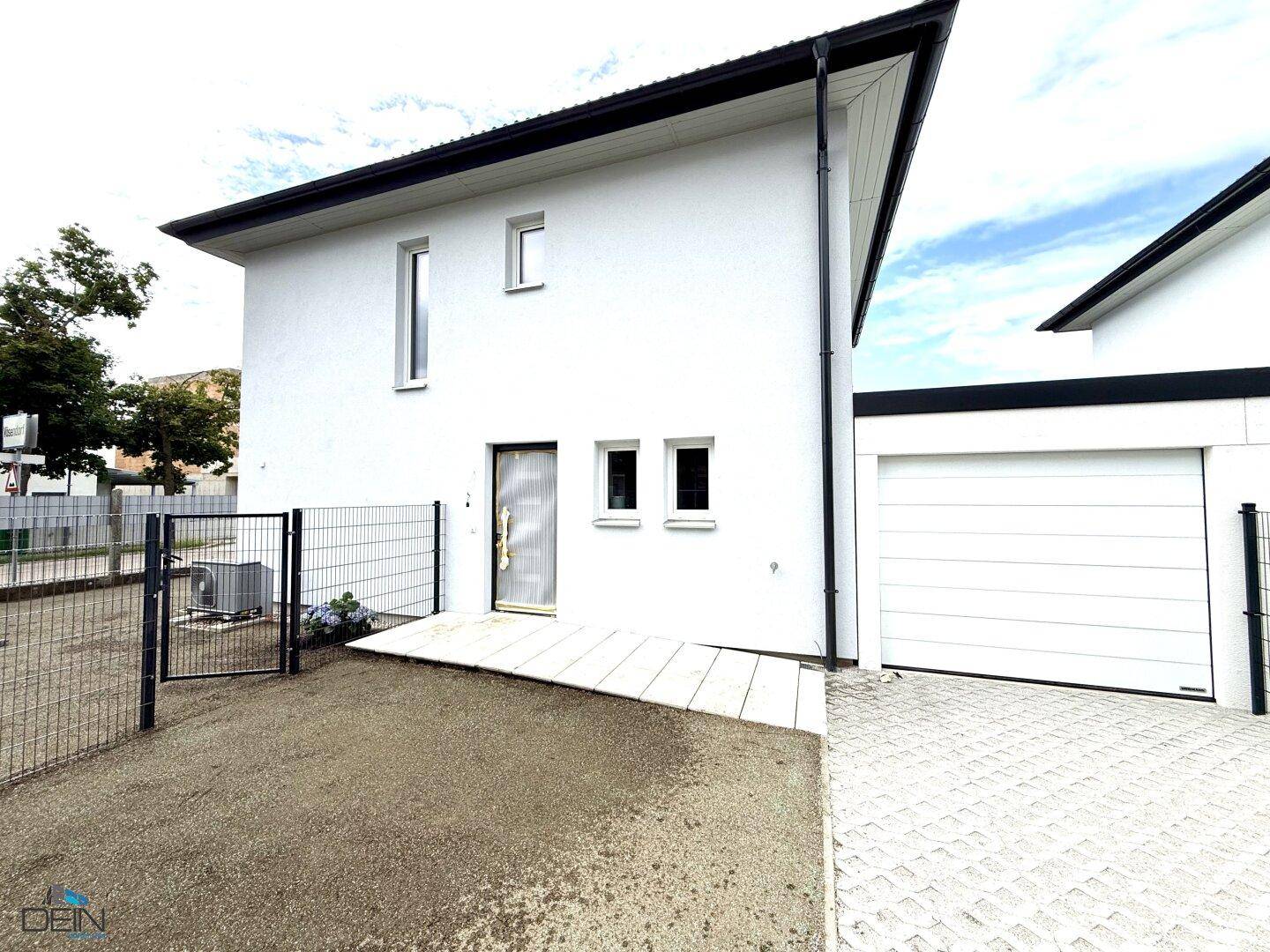 Vorderansicht eines modernen Einfamilienhauses mit integrierter Garage und gepflasterter Zufahrt.