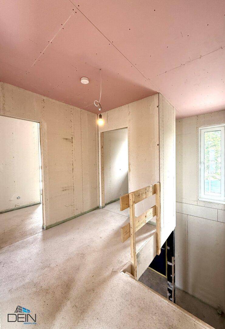 Unfertiger Treppenabsatz im Neubau mit provisorischem Geländer und rosa Deckenplatten.