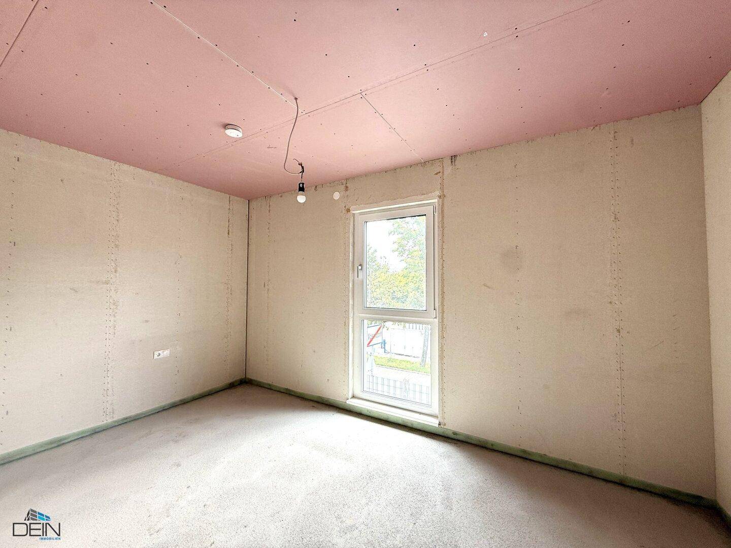 Rohbau-Schlafzimmer mit einem Fenster und rosa Deckenplatten, wartet auf die Fertigstellung.