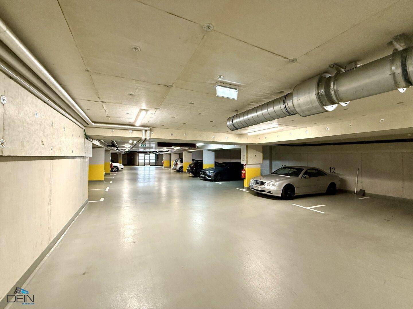 Tiefgarage mit markierten Stellplätzen und mehreren geparkten Fahrzeugen.