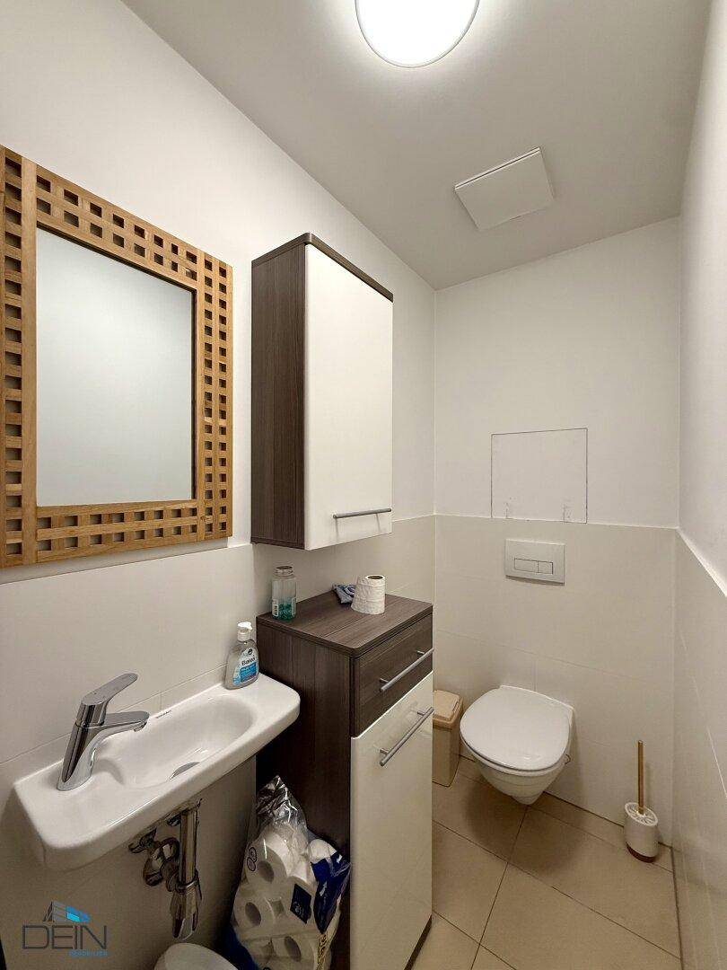 Modernes Gäste-WC mit Wand-WC, kleinem Waschbecken und Fliesenboden.