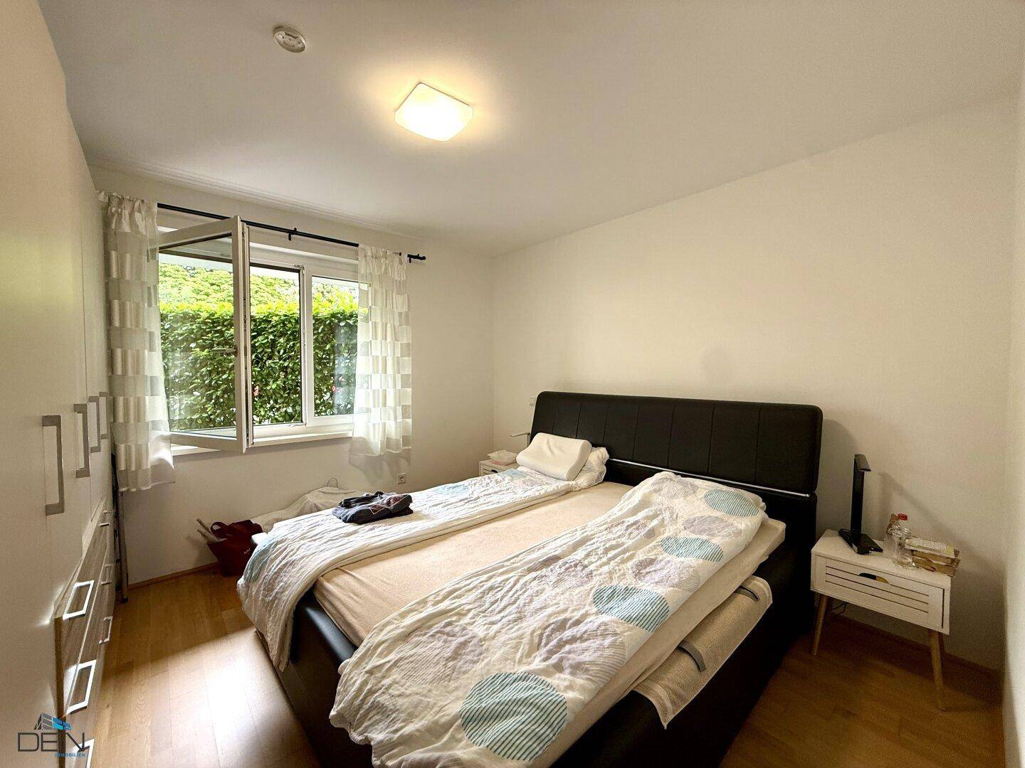 Schlafzimmer mit Doppelbett, weißem Kleiderschrank und Blick ins Grüne.
