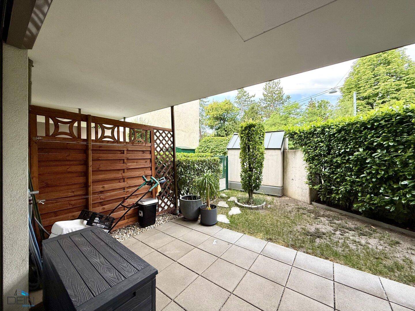 Terrasse mit Holzsichtschutz und Zugang zum privaten Gartenbereich.