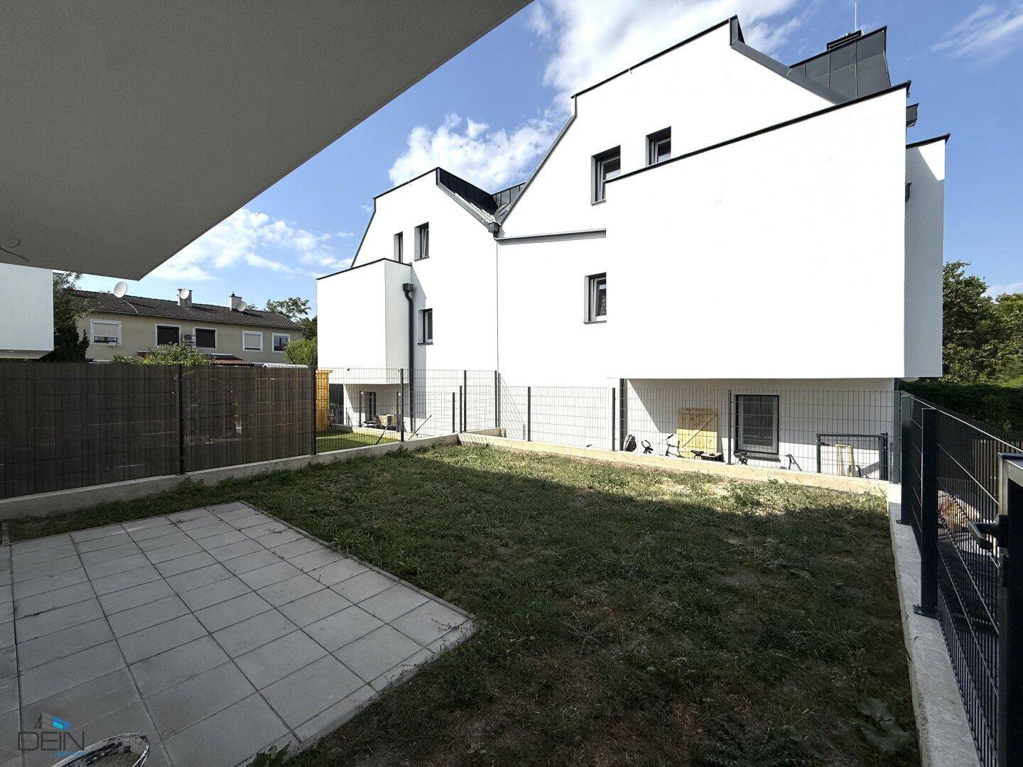 Hinteransicht der modernen Reihenhäuser mit privatem Gartenbereich und Terrasse.