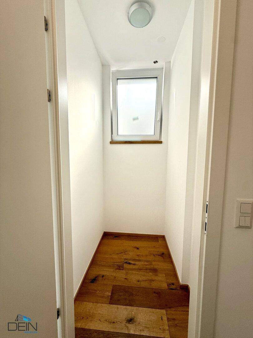 Kleiner Abstellraum mit Fenster und Holzboden, ideal für zusätzlichen Stauraum.
