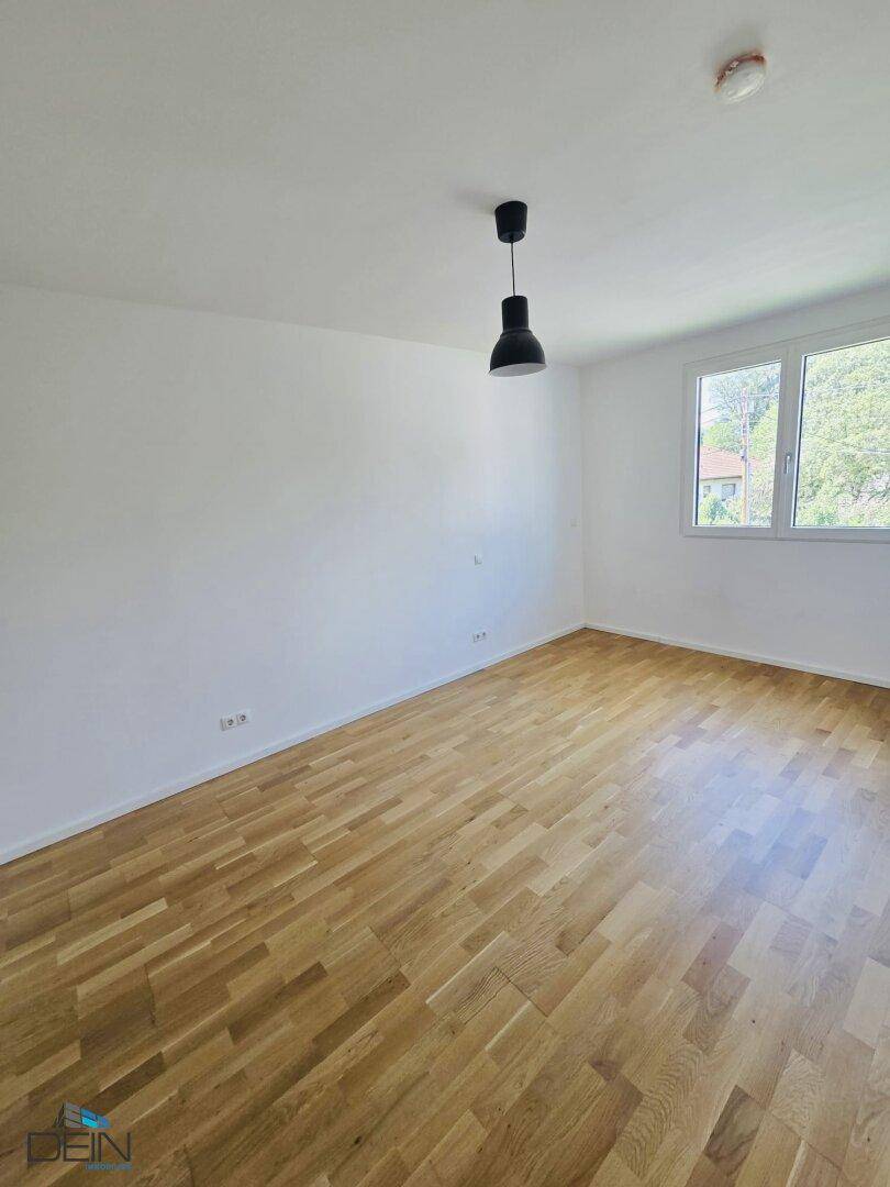 Geräumiges Zimmer mit hellem Parkettboden und großem Fenster für viel Tageslicht.