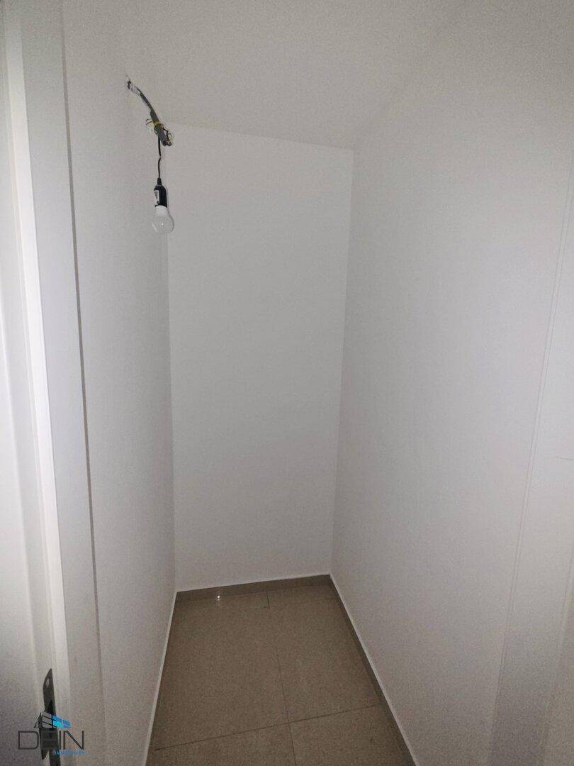 Praktischer Abstellraum mit Fliesenboden und einfacher Beleuchtung für zusätzlichen Stauraum.
