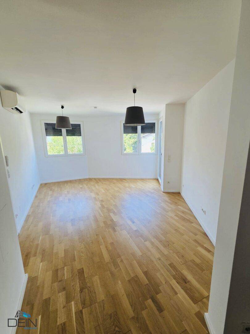 Großzügiges Wohnzimmer mit Parkettboden, Klimaanlage und Zugang zu einem Außenbereich.