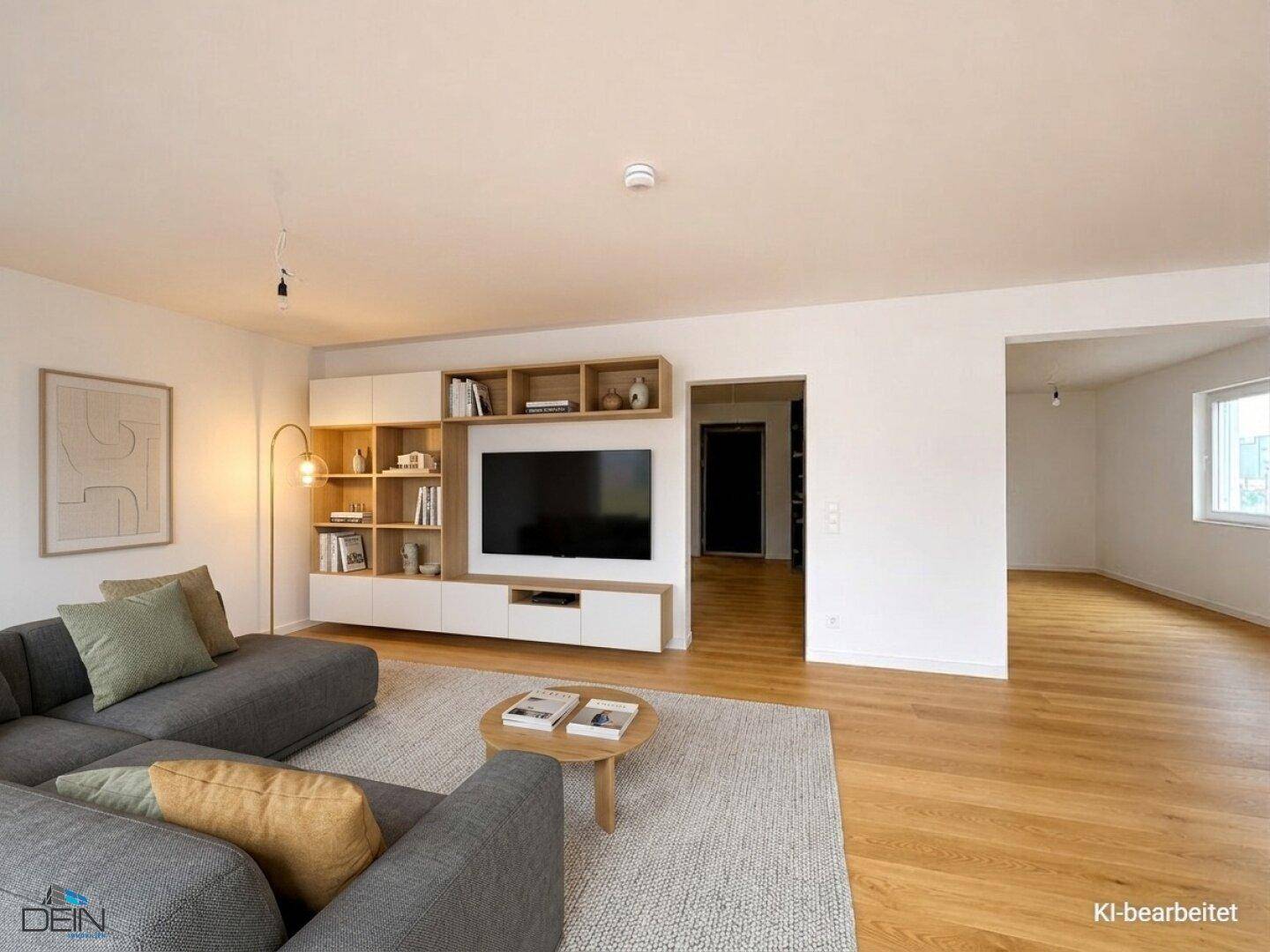 Modernes Wohnzimmer mit Holzboden, großem Sofa und integrierter TV-Wand in hellem Ambiente.