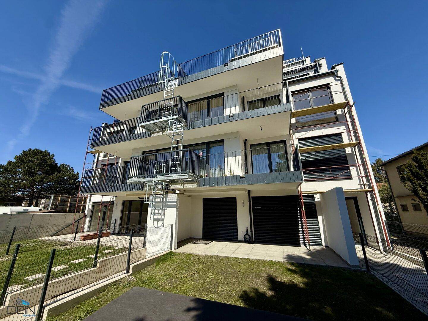Neubau-Wohngebäude mit moderner Architektur, Balkonen und Gerüst an der Seite.